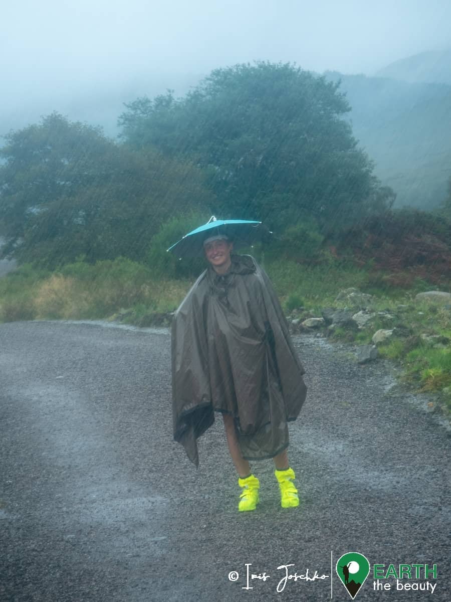 girl with umbrella hat standing in the rain in the middle of a hiking path